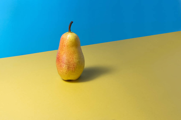 Fruto de pera sobre el fondo azul amarillo. - Foto, imagen