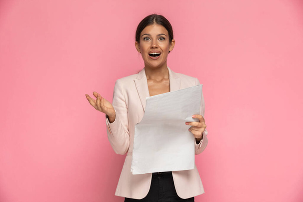 молодая бизнесвумен удивлена новостью, которую она прочитала на розовом фоне - Фото, изображение