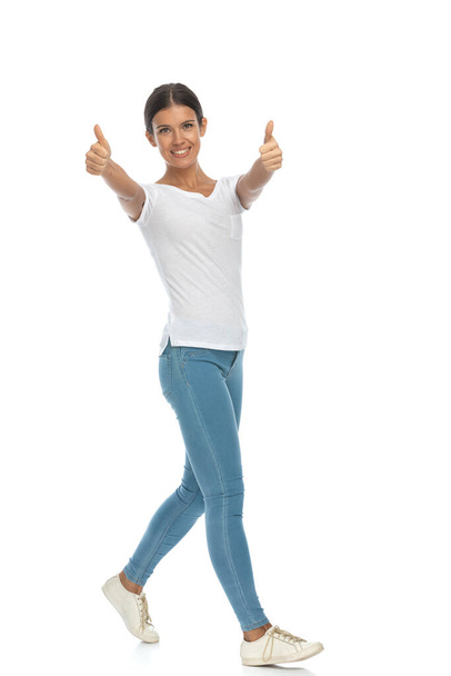 Smiling casual woman gesturing ok with both hands, walking on white studio background - Fotoğraf, Görsel