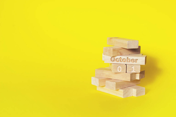 1 de octubre. Día 1 del mes, fecha del calendario. Bloques de madera plegados en la torre con mes y día sobre fondo amarillo, con espacio para copiar. Mes de otoño, concepto del día del año - Foto, imagen