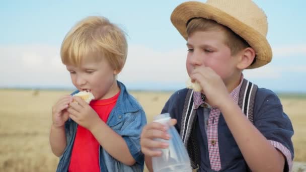 związek dzieci, chłopiec pomaga młodszemu bratu pić mleko z butelki - Materiał filmowy, wideo