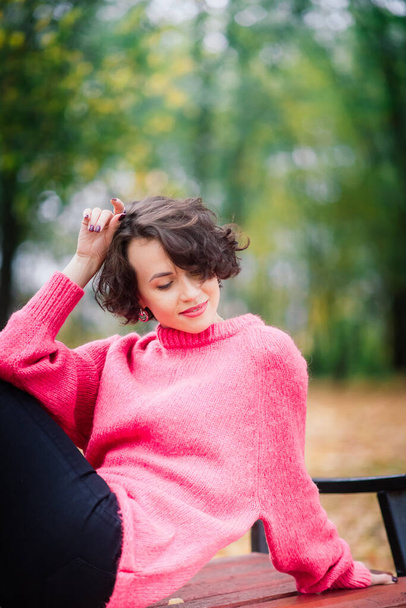 Junge schöne Ballerina in hellem Mantel und Spitzenschuhen sitzen auf der Bank, ruhen sich draußen im Herbstpark aus. - Foto, Bild