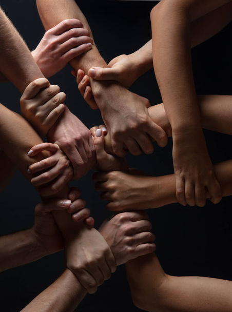 Hands of peoples crowd in touch isolated on black studio background. Concept of human relation, community, togetherness, symbolism - Фото, изображение