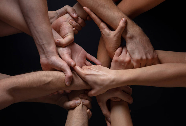 Hands of peoples crowd in touch isolated on black studio background. Concept of human relation, community, togetherness, symbolism - Foto, imagen