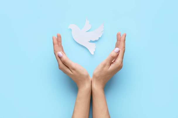 Weibliche Hände mit Papiertaube auf farbigem Hintergrund. Internationaler Friedenstag - Foto, Bild