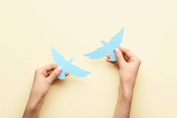 Female hands with paper doves on color background. International Day of Peace - Photo, Image