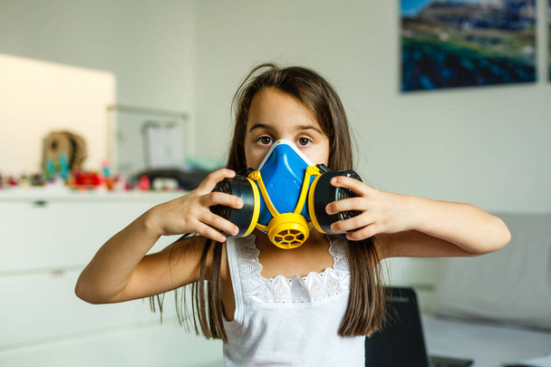 Küçük kızın virüslere karşı koruyucu bir maske taktığı yakın plan görüntüsü ve havada toz.. - Fotoğraf, Görsel