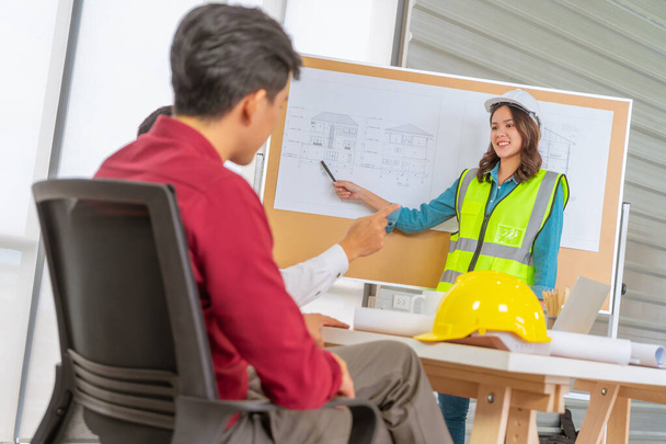 Ingeniera femenina presenta dibujo de plan de construcción a su equipo de contratistas y cliente. - Foto, imagen