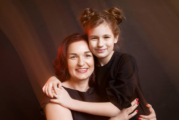 Mother and daughter. Beautiful family. Black background, black clothes, mixed light. - 写真・画像