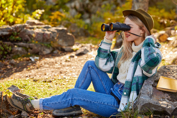 active blonde female in looking at nature through binoculars - Photo, Image