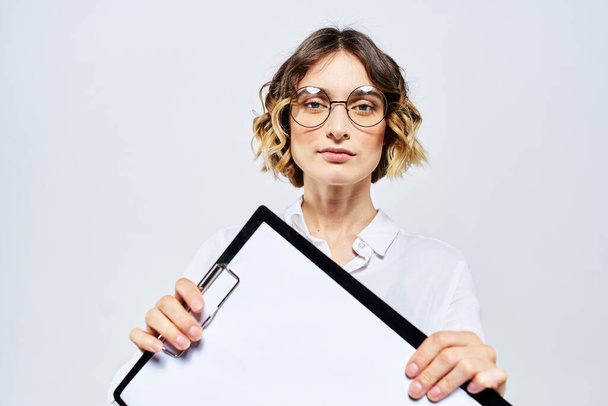 Bizneswoman z teczką białych dokumentów w ręku na jasnym tle i modelką okularów fryzjerskich - Zdjęcie, obraz