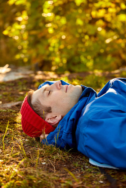 calm caucasian male lie on the grass, relaxing during hiking or camping - Foto, Bild