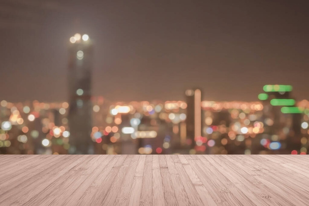 Тераса на дерев'яній підлозі або дерев'яний стіл з розмитим фоном на даху вид на місто нічне світло боке
  - Фото, зображення