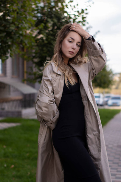 attraente sottile giovane bruna in trench alla moda e vestito nero - Foto, immagini