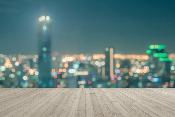 Suelo de madera terraza o mesa de madera con fondo borroso vista de la azotea vista ciudad noche luz bokeh  - Foto, imagen