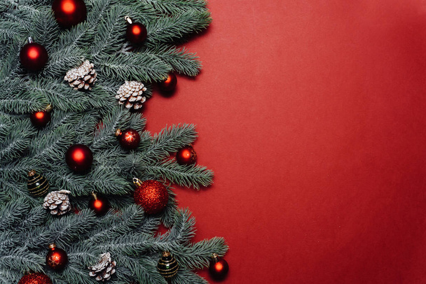 Prostor pro text mezi větvemi vánočních stromků s vánoční ozdobou a míčky na červeném pozadí. Vánoční kompozice. Šťastný Nový rok. Mezera pro text - Fotografie, Obrázek