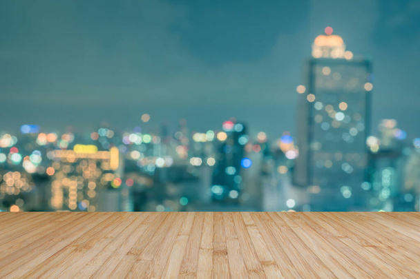 Деревянный пол терраса или деревянный стол с размытым фоном на крыше перспективы города ночь боке  - Фото, изображение