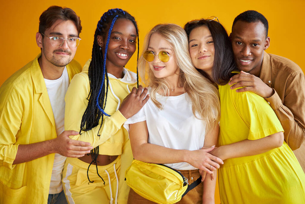 group of happy young men and women isolated on yellow background - Foto, immagini