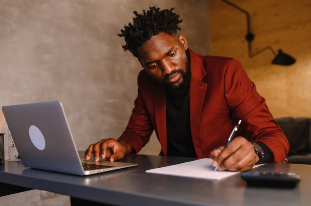  black business man working on laptop and taking notes - Foto, Imagen