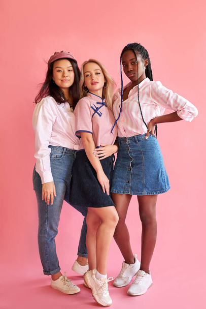 three young women friends of different race posing isolated on bright pink wall background - Fotoğraf, Görsel