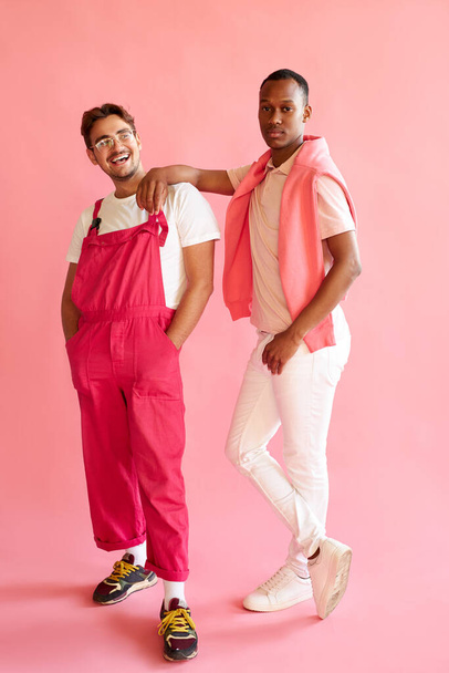 positive caucasian and afro american men in stylish wear posing at camera in studio - 写真・画像