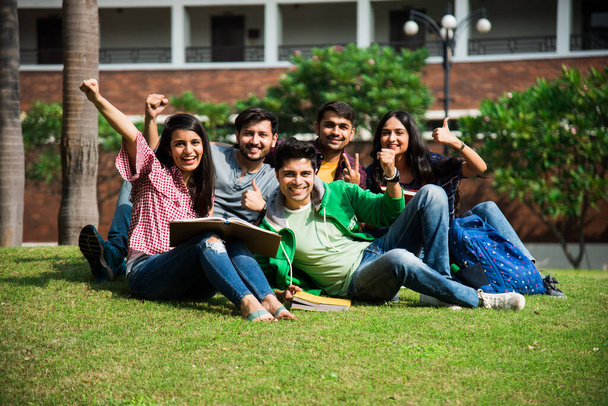 Allegro indiano asiatico giovane gruppo di studenti universitari o amici ridere insieme mentre seduti, in piedi o a piedi nel campus - Foto, immagini