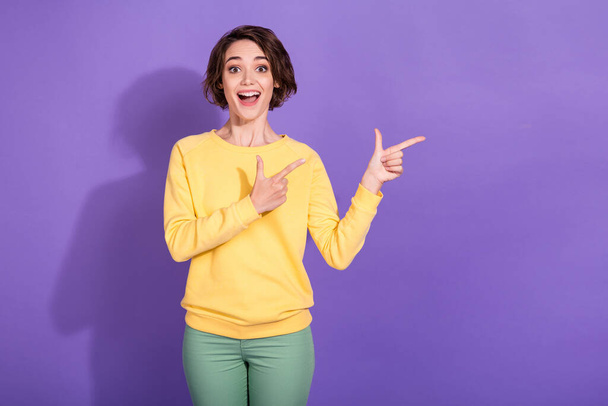 Photo of shocked crazy girl point index finger copyspace wear green pants yellow pullover isolated on violet color background - Zdjęcie, obraz