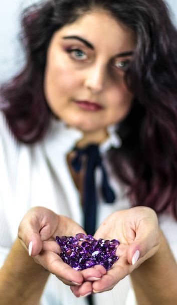 Элегантная женщина держит в руках много драгоценных камней. Блестящие фиолетовые аметисты. - Фото, изображение