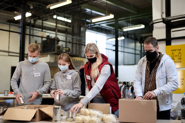 Group of volunteers in community charity donation center, food bank and coronavirus concept. - Foto, afbeelding