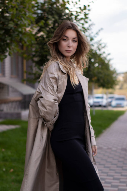 attractive slim young brunette in fashionable trench coat and black dress - Fotoğraf, Görsel