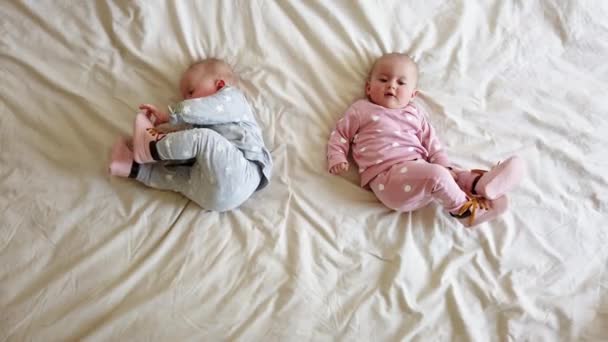 Dos hermanas se acuestan en la cama. Dos bebés gemelos en la cama - Metraje, vídeo