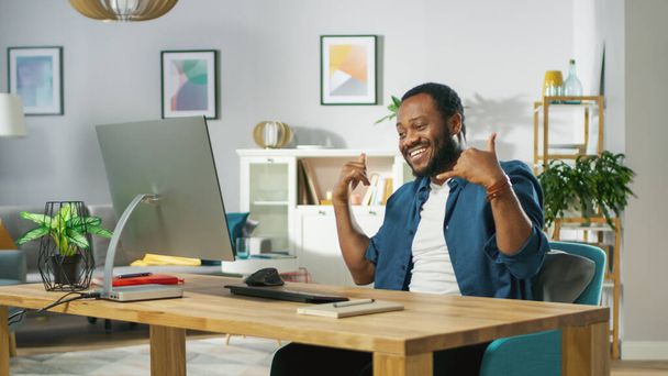 Excited Young Man Uses Personal Computer at Home, Talk With Friend and Does "Shaka sign" Gesture. In the Background Cozy Living Room. - Fotoğraf, Görsel