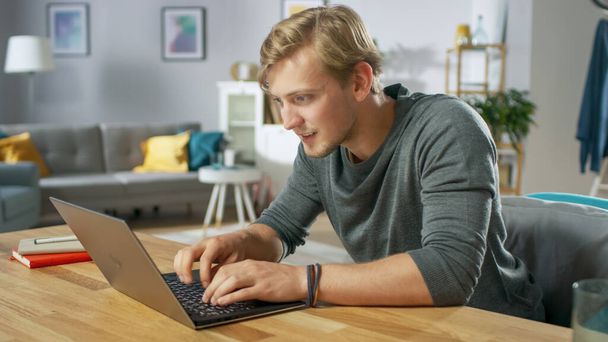 Handsome Young Man Using Laptop While Sitting at the Desk of His Cozy Living Room. - Photo, Image
