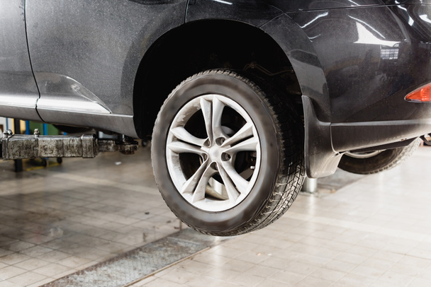 front wheels of modern car raised in workshop for maintenance - Foto, afbeelding