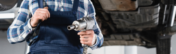 cropped view of mechanic holding pneumatic wrench on blurred background, banner - Photo, Image