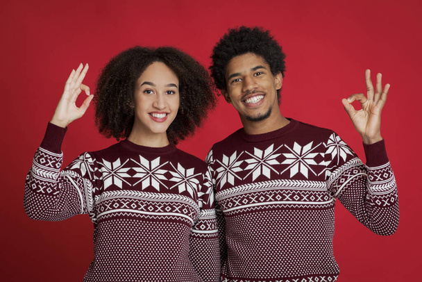 Alegre afroamericano familia en idénticos suéteres mostrar signo bien con sus manos y mirar a la cámara - Foto, imagen