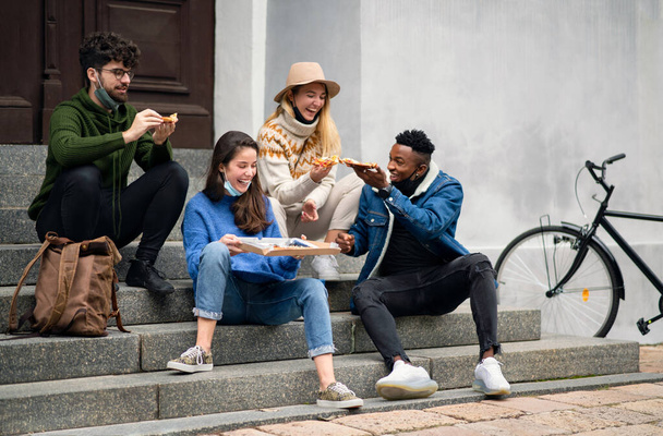 Group of young people outdoors in town, eating pizza. Coronavirus concept. - Fotó, kép