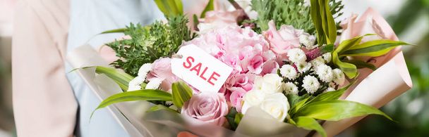 vista ritagliata del fiorista che tiene bouquet con scritte in vendita su etichetta, banner - Foto, immagini