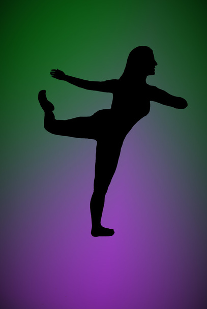 Silhouette of a woman dancing with a green and purple background - Zdjęcie, obraz