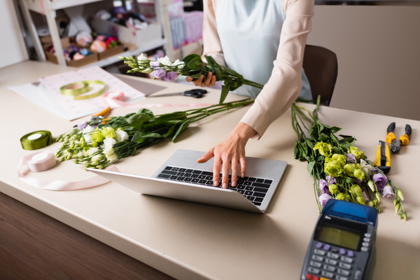 vágott kilátás virágárus laptoppal közel fizetési terminál és eustoma virágok az asztalon - Fotó, kép