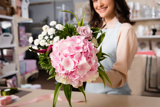 Close up view of bouquet in hand of female florist on blurred background - Photo, Image
