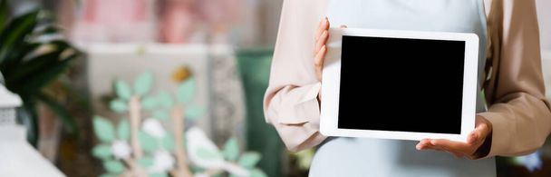 Cropped view of female florist holding digital tablet with blank screen on blurred background, banner - Fotó, kép