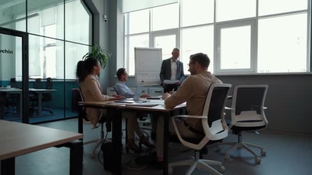 Αρσενικό επικεφαλής της ομάδας ή εκτελεστικό εξηγώντας επιχειρηματική στρατηγική στο λευκό πίνακα στους συναδέλφους, δίνοντας την παρουσίαση - Πλάνα, βίντεο
