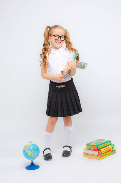 uma menina em uniforme escolar e óculos segurando livro  - Foto, Imagem