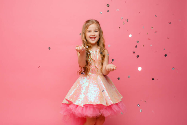 heureuse petite fille attrape confettis sur fond rose, concept de vacances - Photo, image