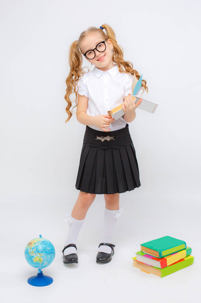 egy kislány iskolai egyenruhában és szemüvegben a kezében könyv  - Fotó, kép