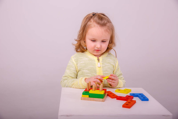 pequena menina loira bonito jogando em um construtor em um fundo branco. Conceito de educação pré-escolar - Foto, Imagem