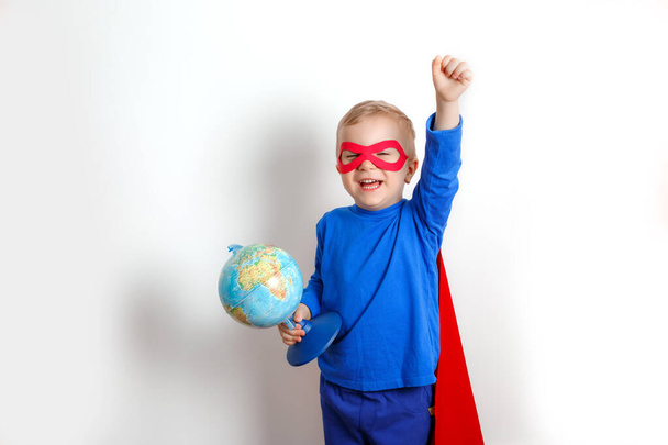 Glücklicher Superheldenjunge, der eine Weltkugel in der Hand hält, das Konzept der Rettung der Welt auf weißem Hintergrund - Foto, Bild