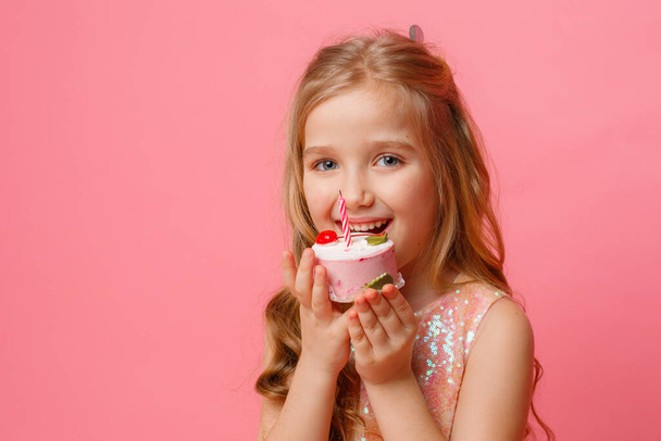 cute little girl posing against pink background with birthday cupcake - Fotoğraf, Görsel