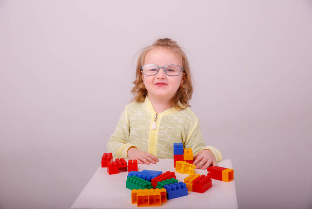 little cute blonde girl playing in a constructor on a white background. Concept of preschool education - Photo, Image